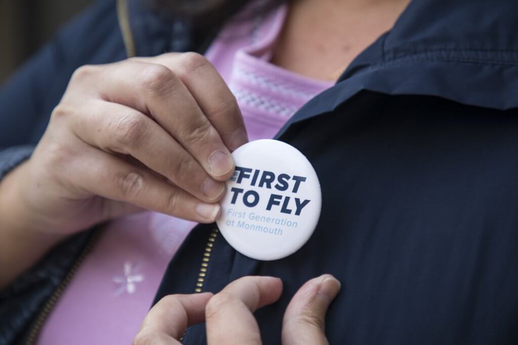 Woman putting a "First to Fly" badge on her jacket.