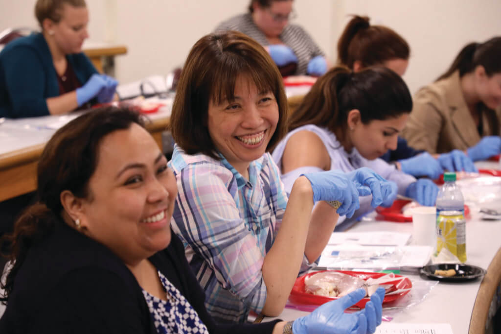 Students smiling, wearing medical gloves and working on project