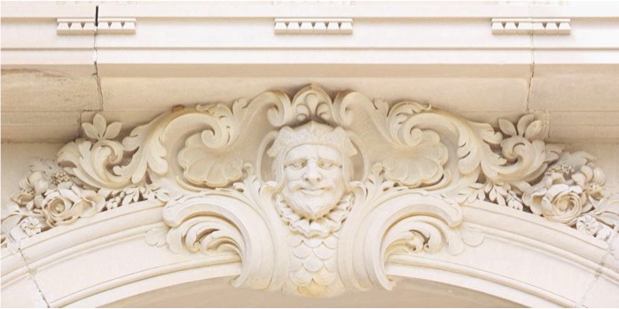 A detailed photo of a carved face at the pinnacle of an archway