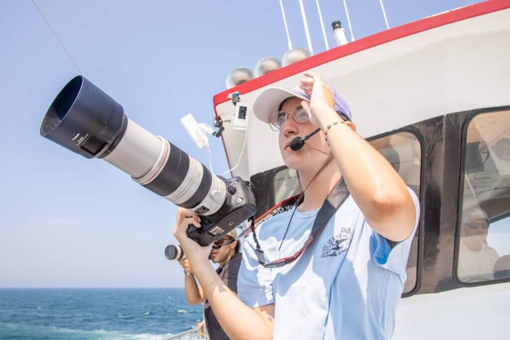 Woman on boat holding a camera, looking out into the distance