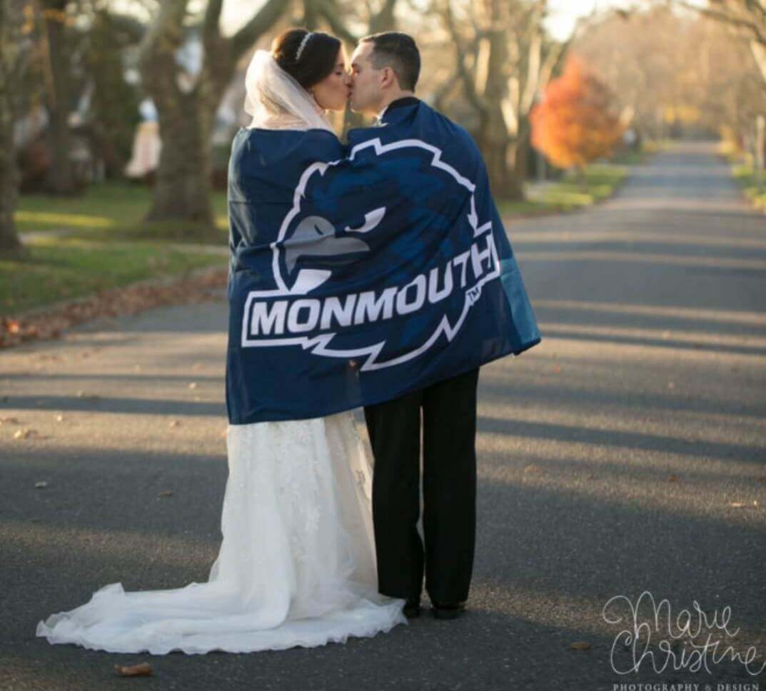 A wedding couple sharing a kiss under a Monmouth University banner