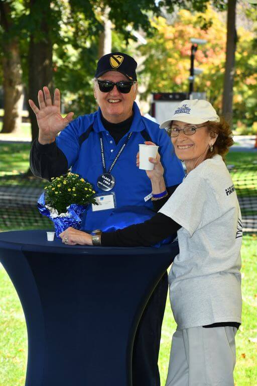 Alumni posing for a photo at a table on the great lawn