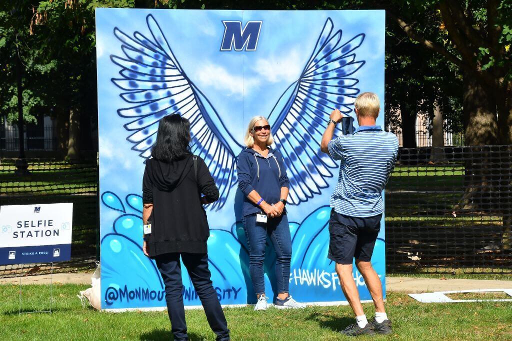 Woman getting photo taken in front of a poster with Hawk wings, as though she had wings herself
