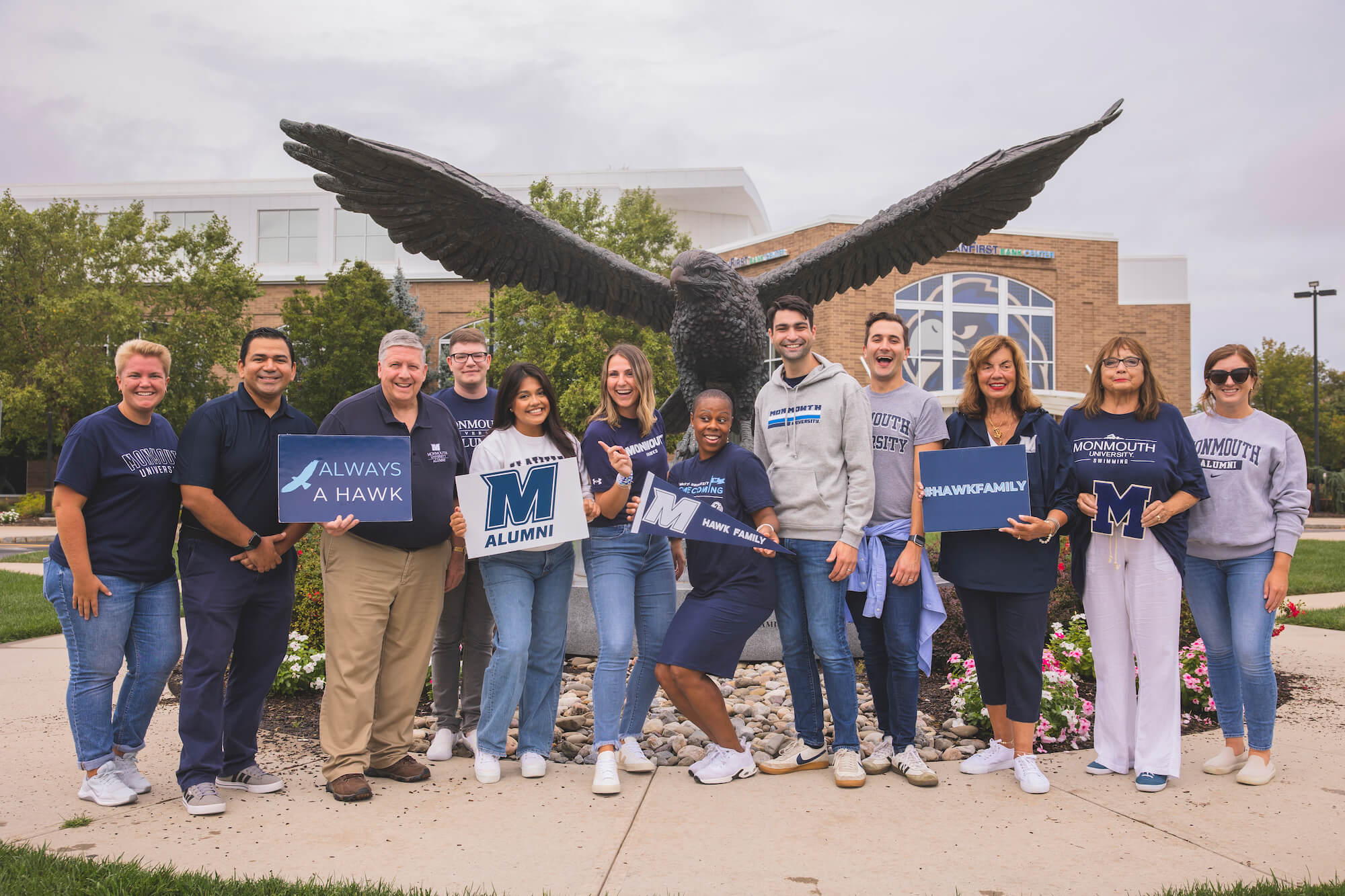 Alumni pose in front of the hawk statue by OceanFirst Bank Center
