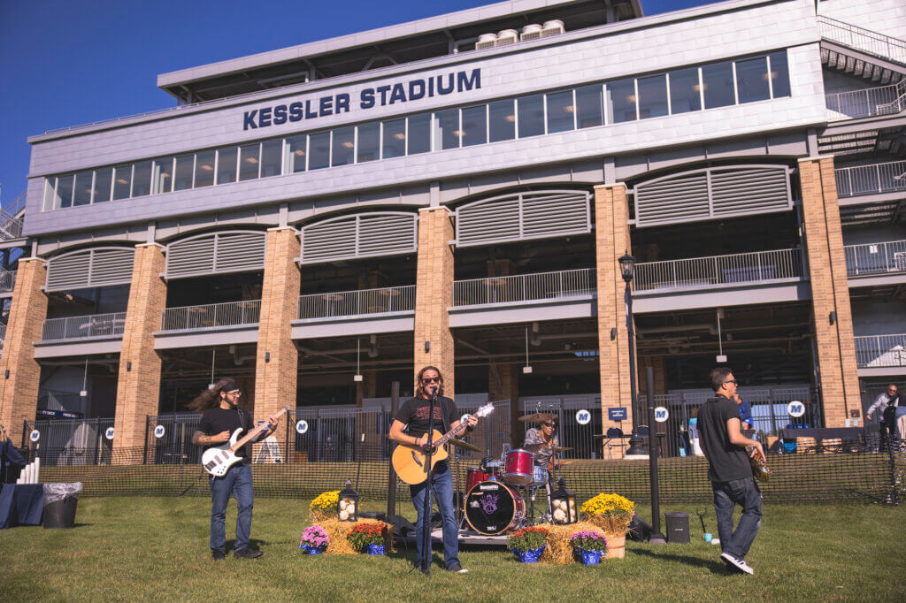 Band playing music on a field in front of a stadium
