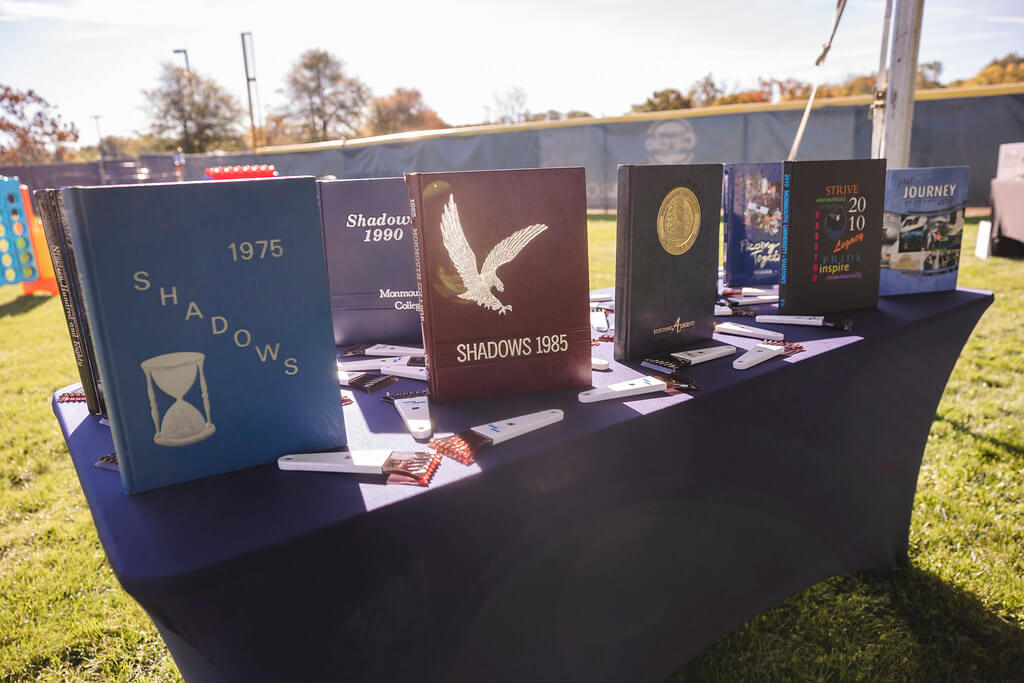 Table of yearbooks at the Milestone Tent. Features Yearbooks from 1975, 1985, 1990, 2010 and others