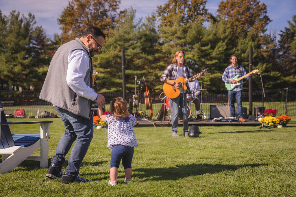 Dad and baby daughter dancing in front of the band at Homecoming Tailgate