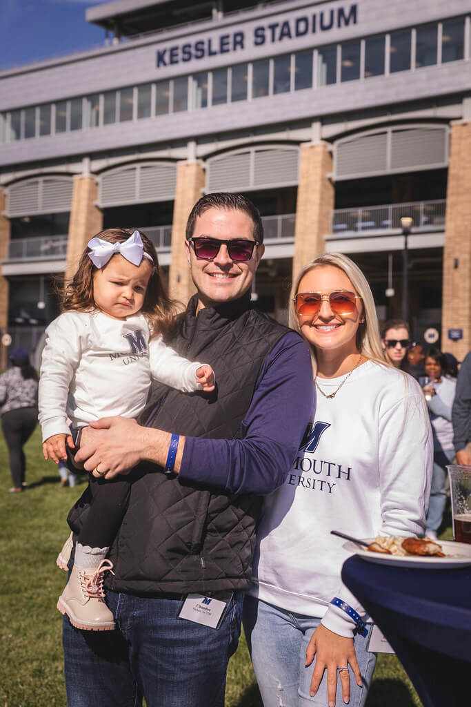 mom and dad holding baby daughter in front of Kessler Stadium