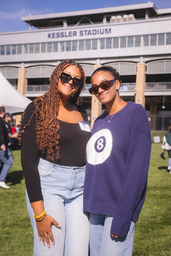 2 young ladies standing together and smiling with Kessler Stadium in the background