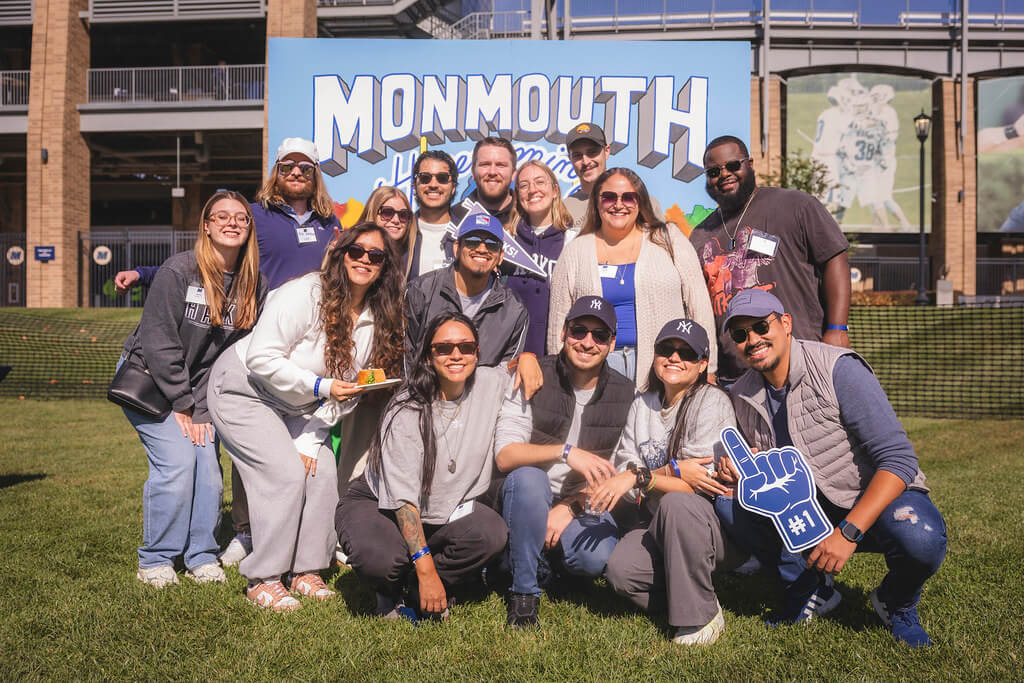 group of 15 friends in front of the decorative Homecoming backdrop