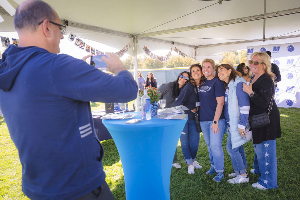 man taking photo of 5 women at the Milestone tent