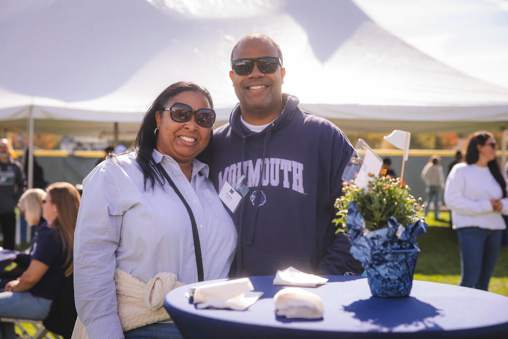couple standing and smiling at hightop table with festive mums