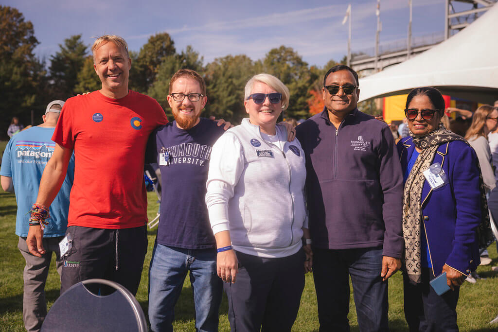 group of 5 people standing in front of the Homecoming Tailgate tent smiling