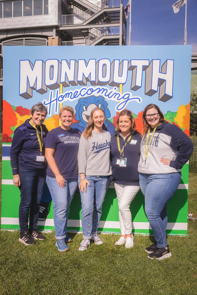 Alumni Engagement and Annual Giving Staff posed in front of the Homecoming decorative backdrop