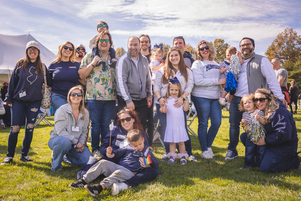 large groups of alumni and their children with monmouth gear, pom poms and photo props at the Homecoming Tailgate