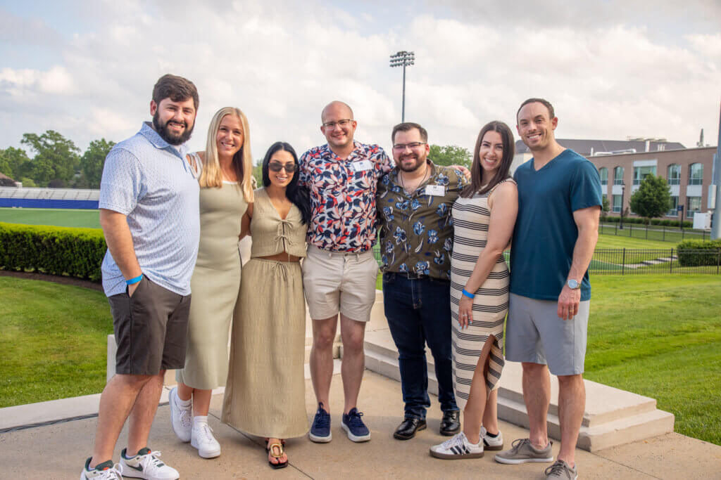 A group of Monmouth University alumni gathering to take a photo outside of the Great Hall.