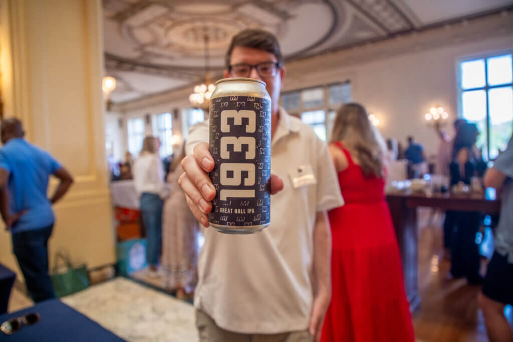 An event volunteer holding up a customized University drink.