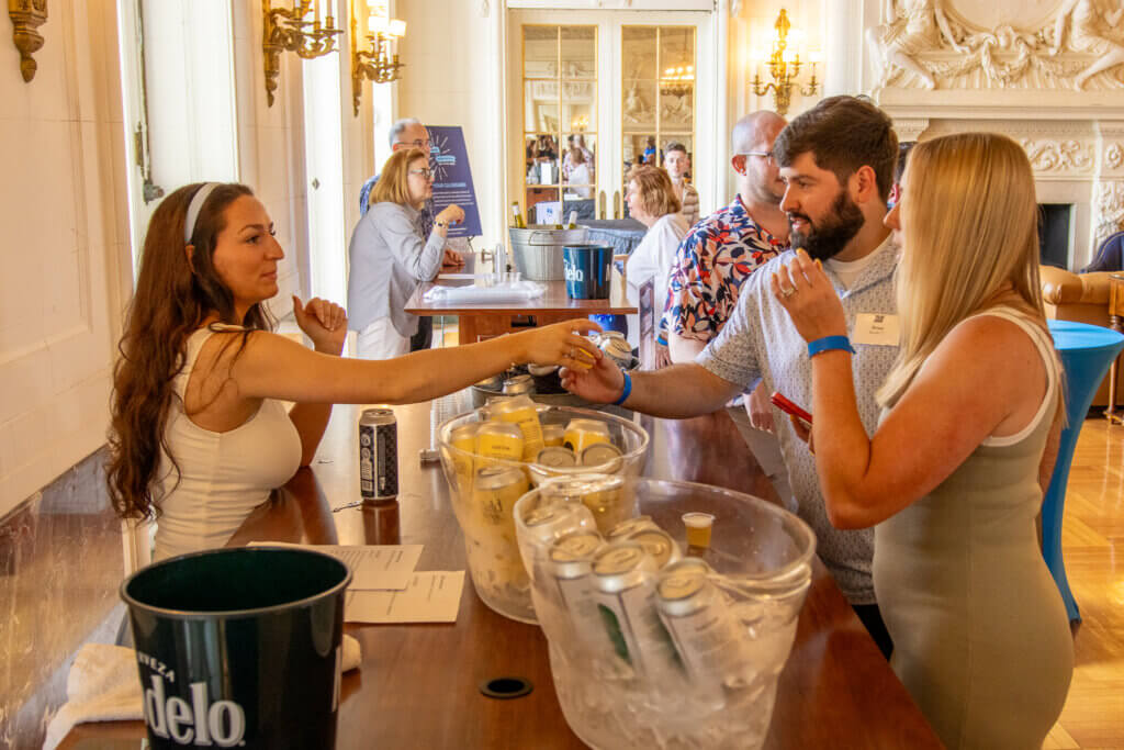 Two alumni tasting a sample wine from the varieties of small bars in the Great Hall.