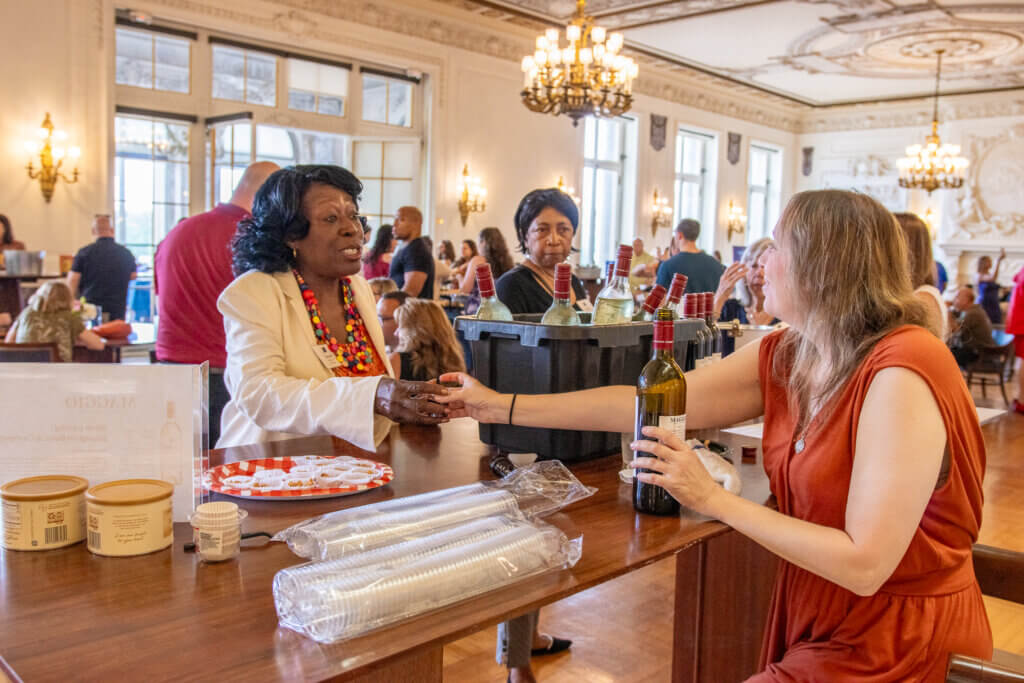 Volunteers chatting with alumni while pouring them sample drinks.