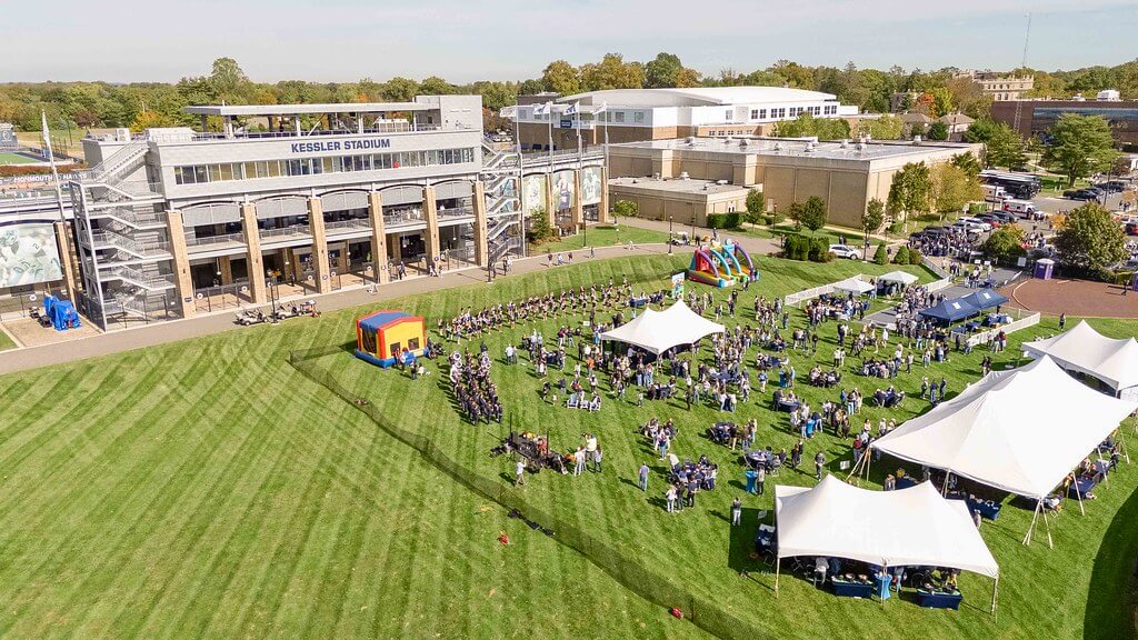Birds-eye view shot of the homecoming tailgate, with tents arranged and a crowd of people enjoying the festivities.