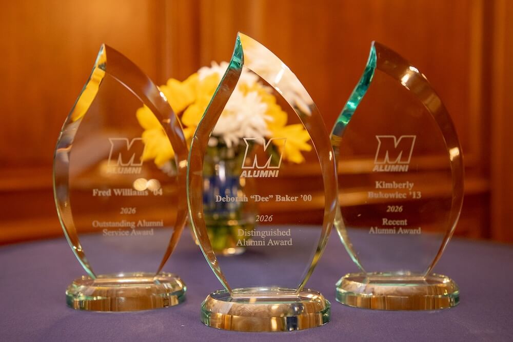 Three glass award statues, one for Fred Williams, one for Deborah 'Dee' Baker, and one for Kimberly Bukowiec, for the alumni awards.