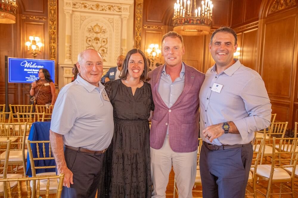 Three men and a woman posing together for photo in award ceremony room