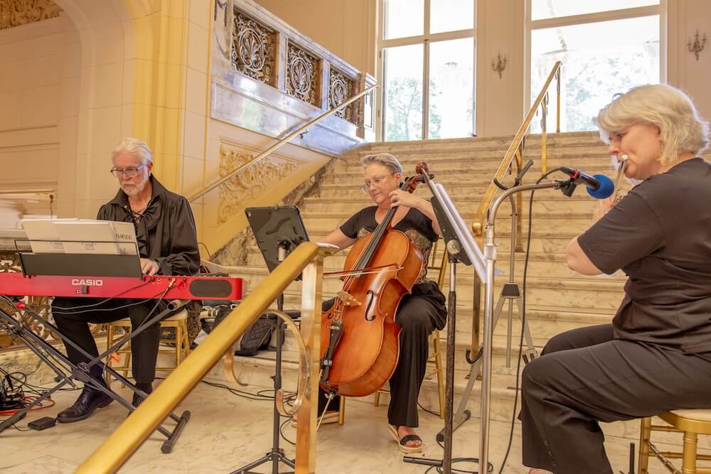 Small band playing on the steps of the Great Hall (keyboardist, cellist, and flute player)