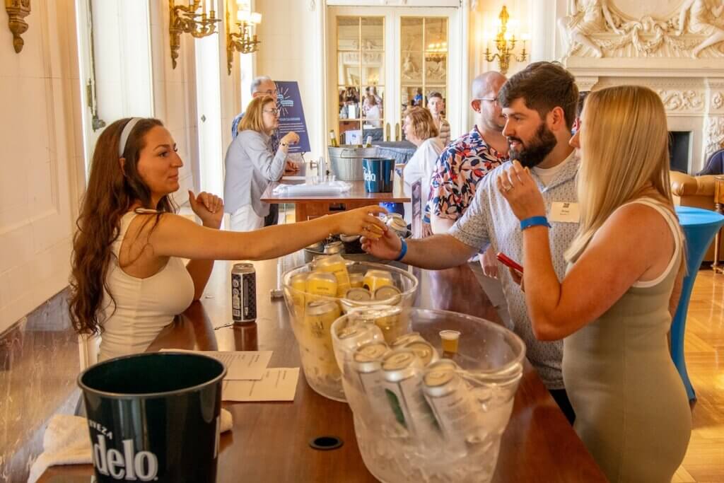 Woman at beer table assisting patrons in ornate hall during Wine and Stein