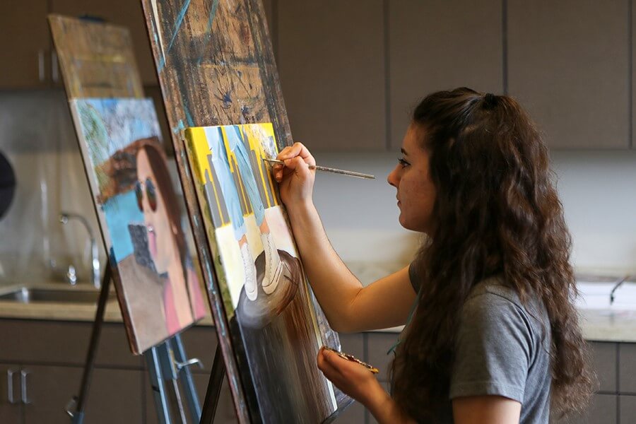 Photograph of a student painting in a studio.