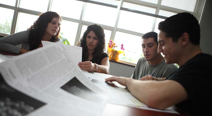 Photo: Members of The Outlook looking over drafts of newspaper pages.