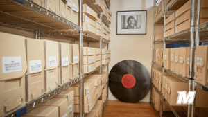 A framed photo of Bruce Springsteen above a vinyl record, boxes on shelves at the sides of the image