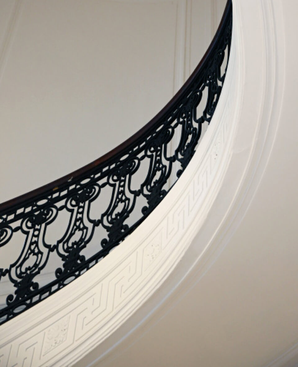 a close up photo of a curved set of stairs with a intricate banister 