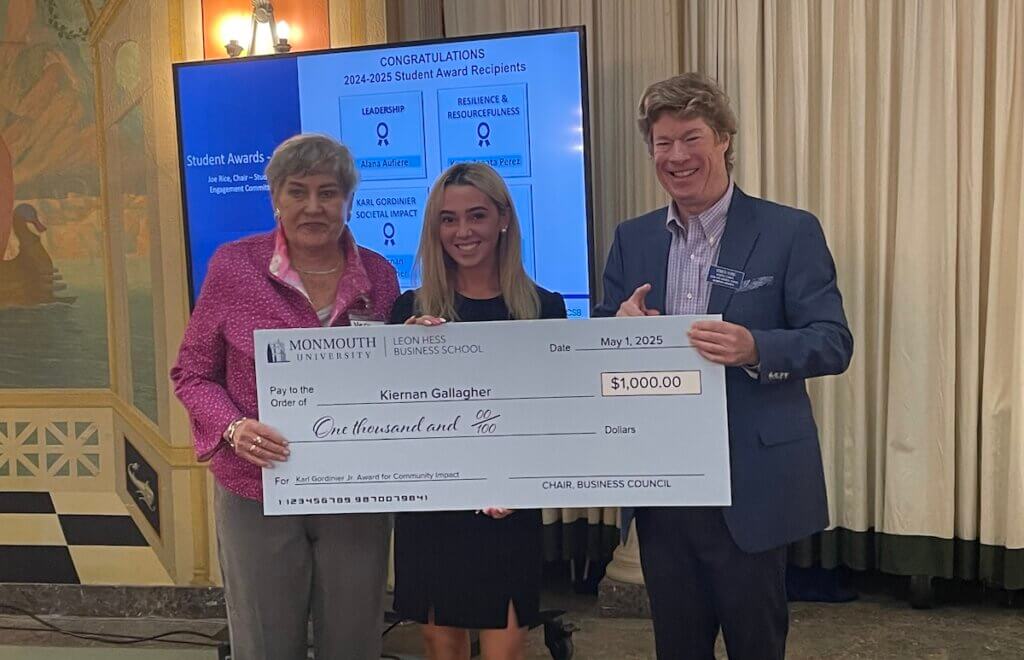 Two professionals and a student holding an oversized check for $1,000