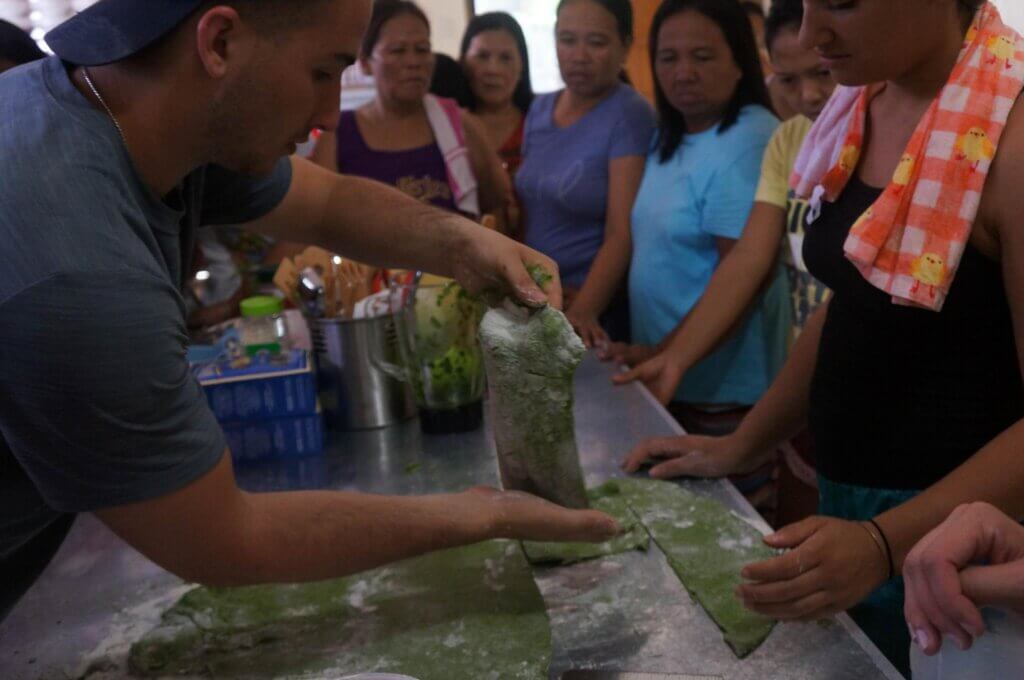 A person demonstrating how to work with dough to a group of students