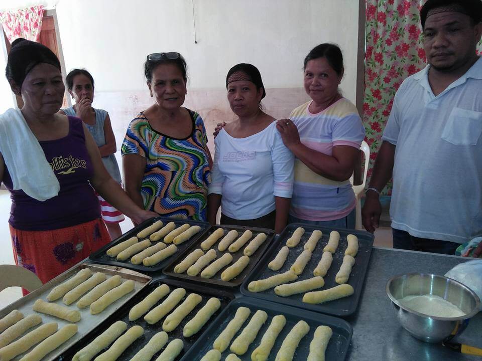 a group of people seeing how to prepare a rolled dough 