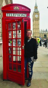 Female study abroad student poses with phone booth in England