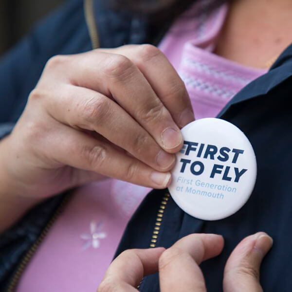 Photo shows person wearing First to Fly button on lapel