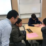 Photo shows Dr. Pang helping a student with the abacus