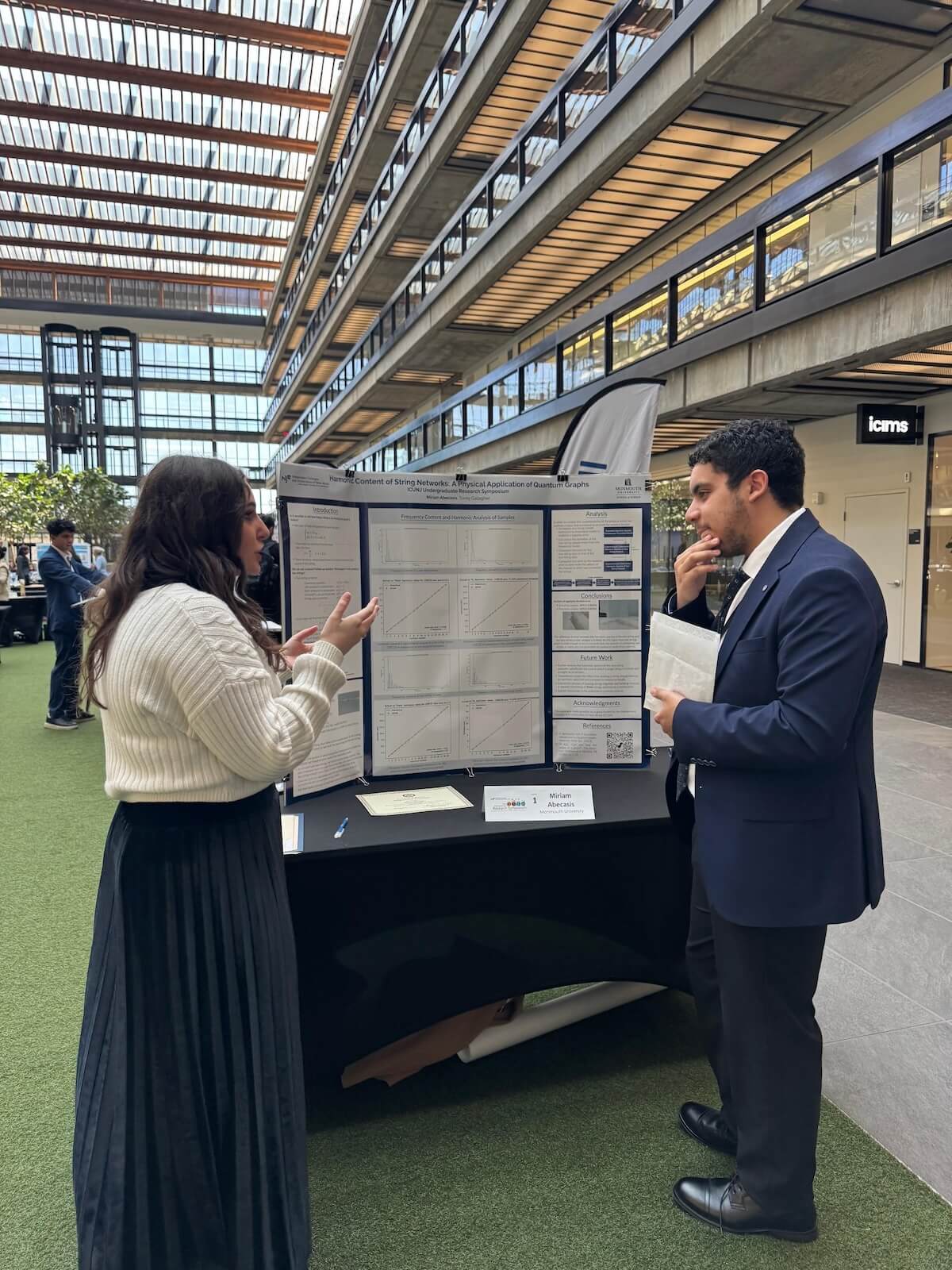 Woman speaking to man about her poster presentation