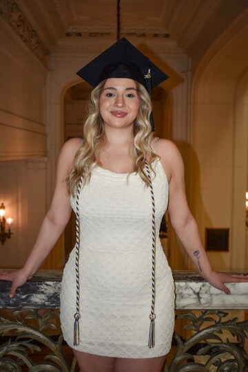 Woman in white dress wearing graduation cap and tassles