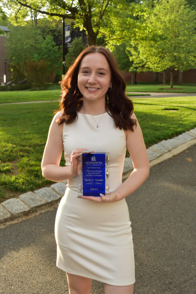 Woman in white dress holding an award that reads "Monmouth University Mathematics Outstanding Academic Achievement Award, Rachel A. Vassallo, 2025".