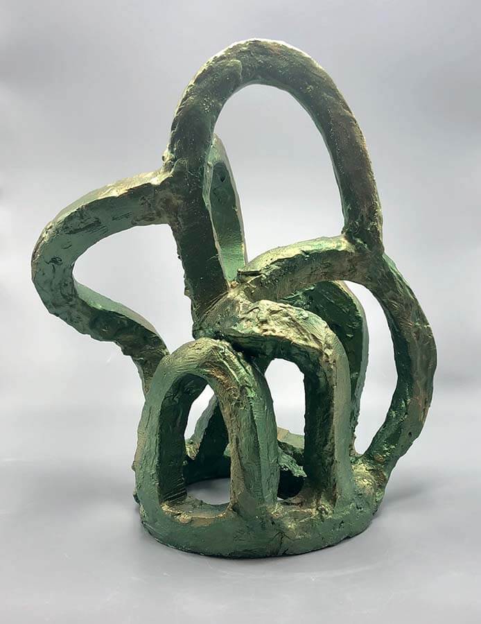 Green abstract sculpture made of thick looping forms that interweave into an open, cage-like structure.