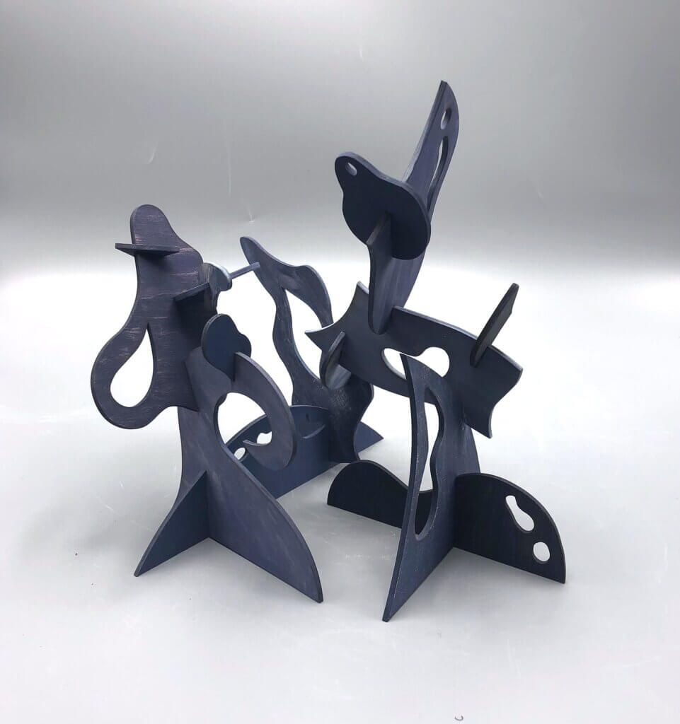 Dark abstract tabletop sculpture made of interlocking cutout shapes and curved forms arranged in an open composition.