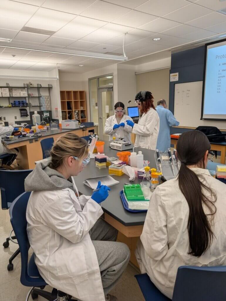 Students in a lab taking notes at a table