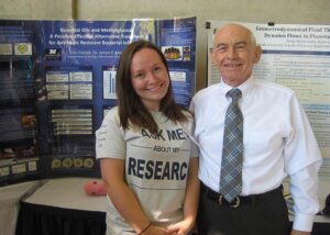 A student and her professor posing for a photo in front of a poster presentation