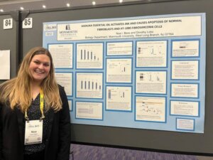 Woman wearing lanyard, standing in front of poster presentation