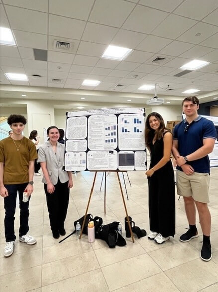 Four students standing in front of poster presentation