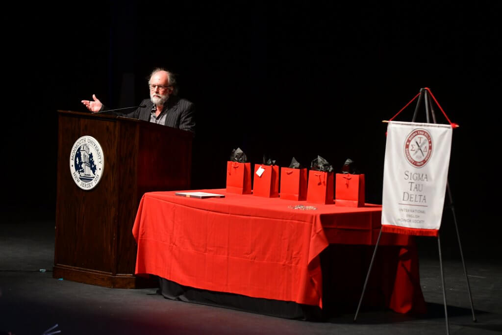 Photo shows Dr. Michael Waters, Professor in the Department of English, opening the Induction Ceremony with a poetry reading.