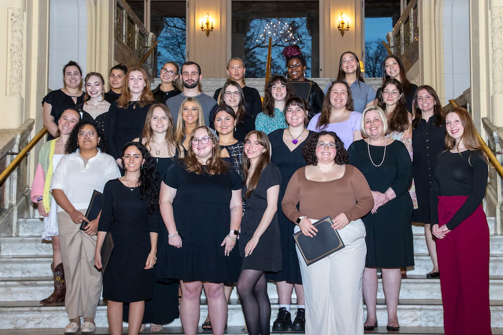 Group of people standing together for a photo on a staircase in the Great Hall.