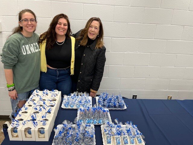 Three women pose for a photo in front of baked goods